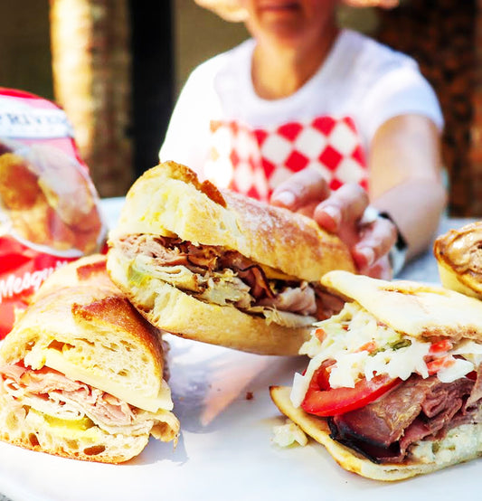 Woman wearing a Red And White Diamond NEATsheet as she reaches for a sandwich.