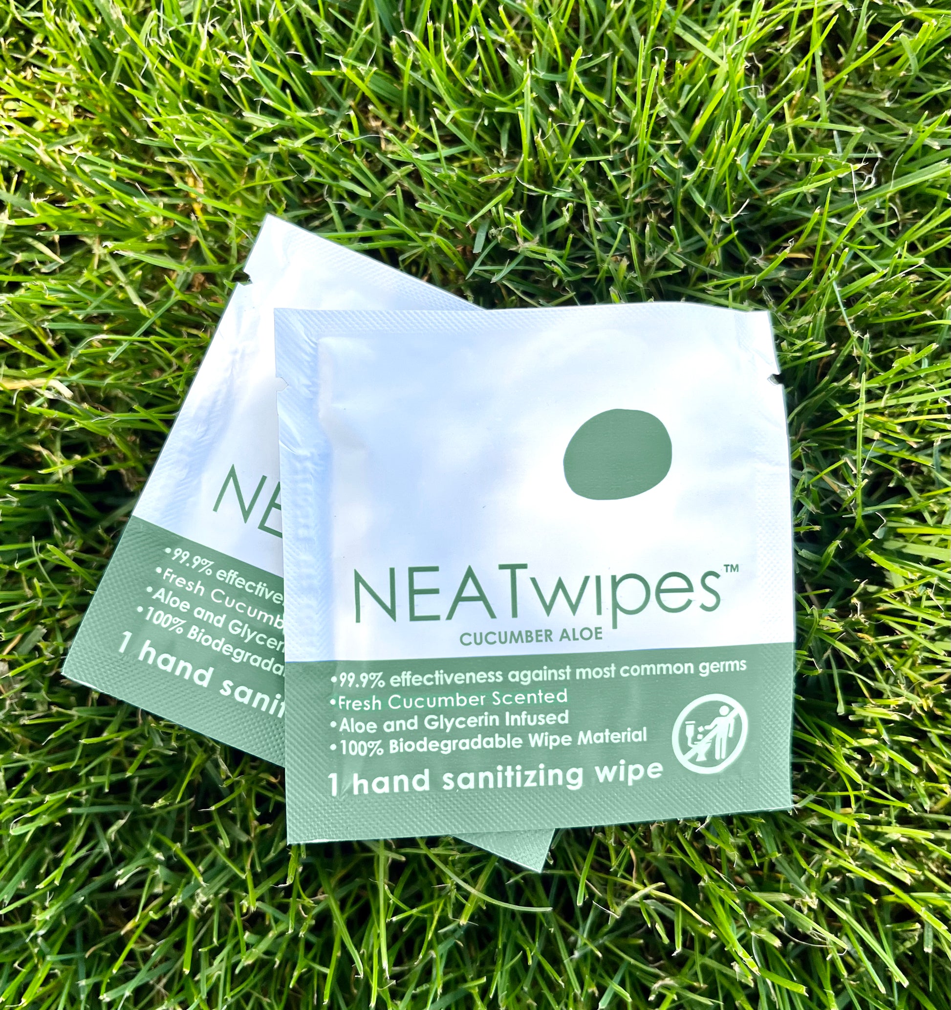 Individually wrapped NEATwipes Cucumber Aloe hand wipes on grass..