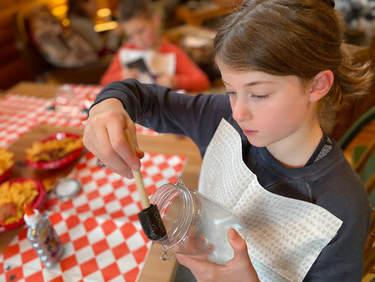 Girl painting a jar doing crafts wearing a Grey Dot NEATsheet.