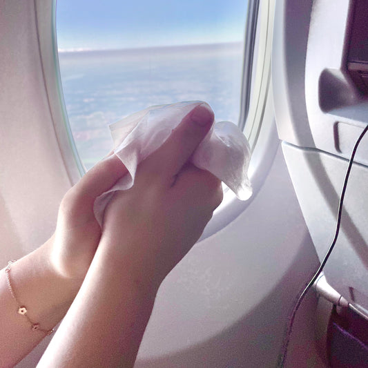 Woman on a plane cleaning her hands with NEATwipes, a calming, soothing, and germ-free hand wipe experience. 