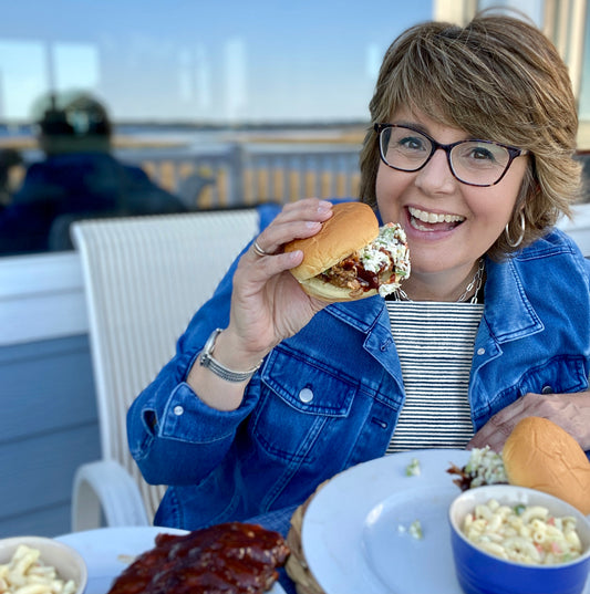 A woman eating a cheeseburger while wearing a Blue Ticking NEATsheet.