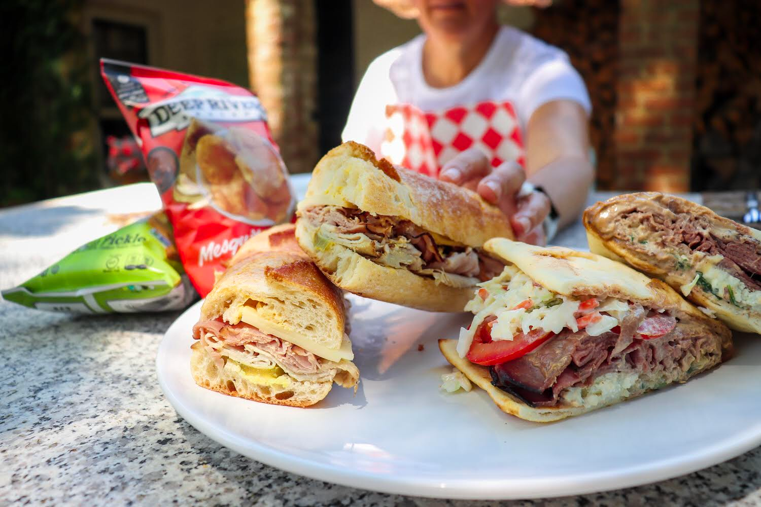 A woman reaching for sandwiches wearing a NEATsheet with Red & White Diamond design,.