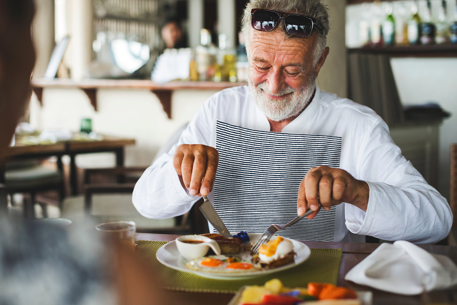 Senior aged man wearing a NEATsheet with Blue Ticking pattern while enjoying brunch.