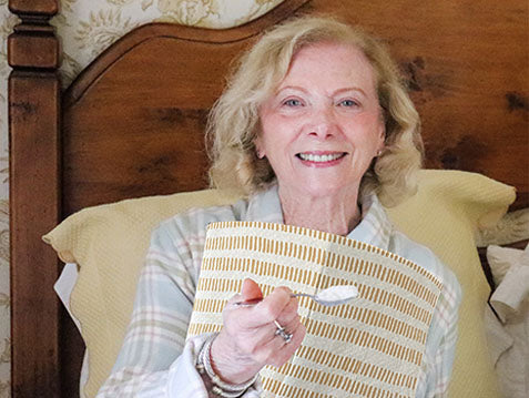 A woman eating breakfast wearing a NEATsheet with Cinnamon Stick design. 