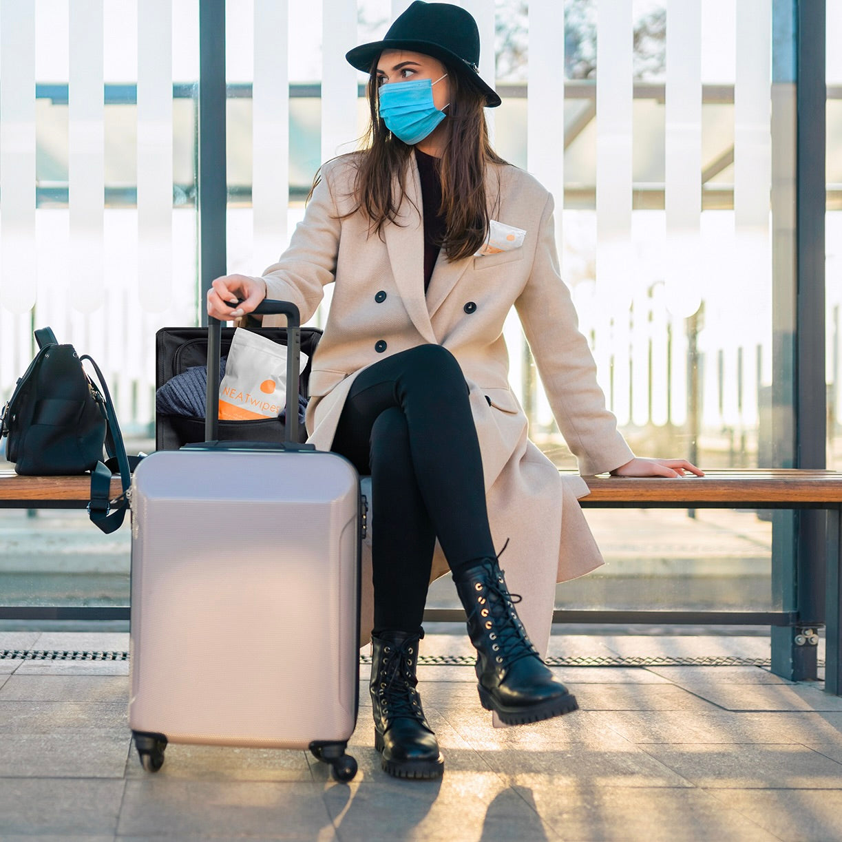 A woman traveling with a 24-Count pouch of NEATwipes Fresh Citrus hand wipes.