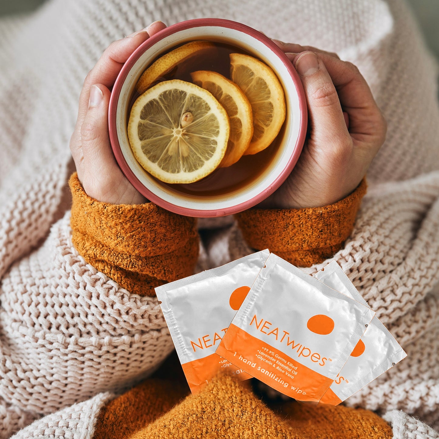 Individually wrapped NEATwipes Fresh Citrus hand wipes by a cup of tea.