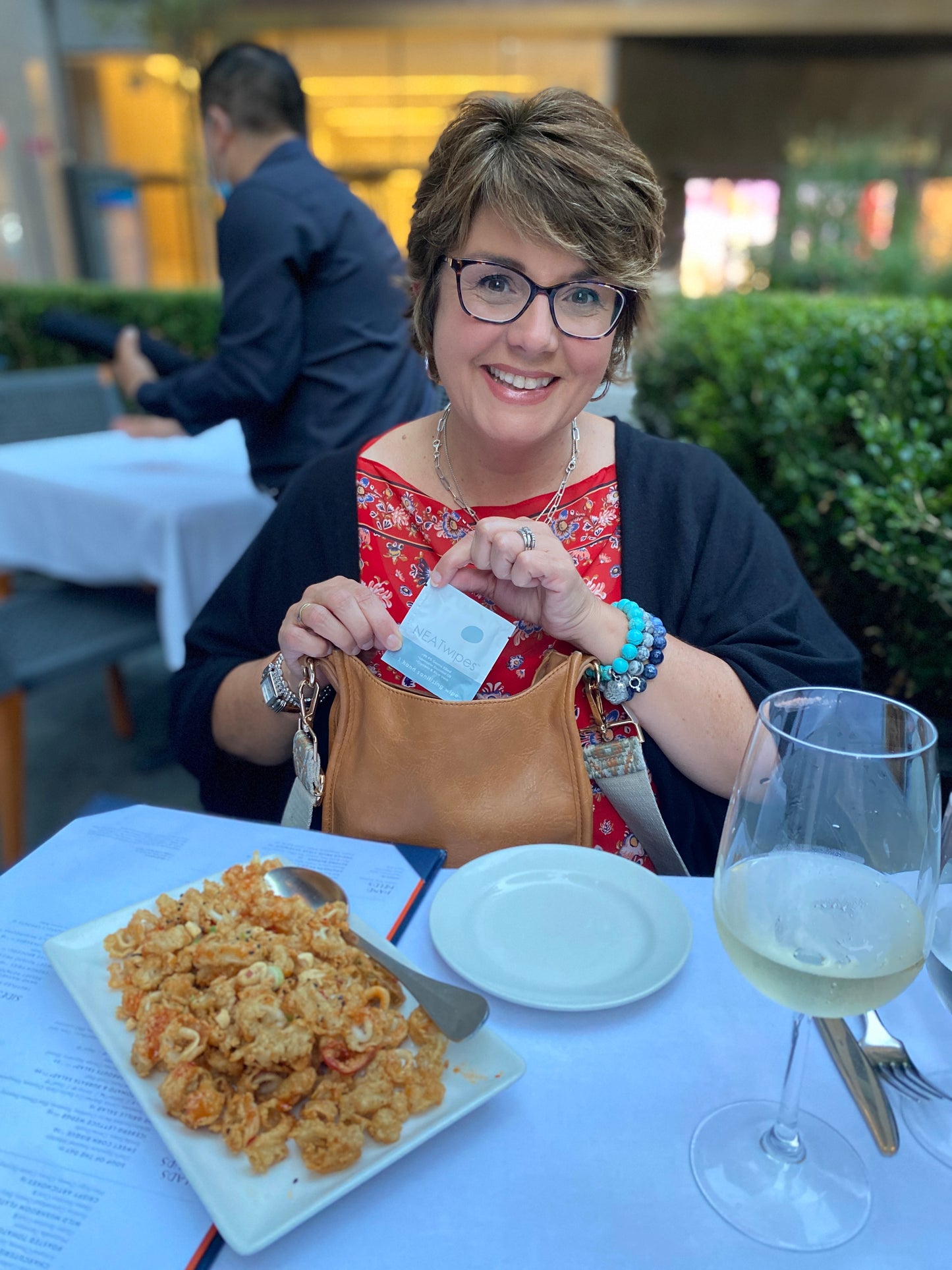 A woman using a NEATwipes Lavender hand wipe at lunch.